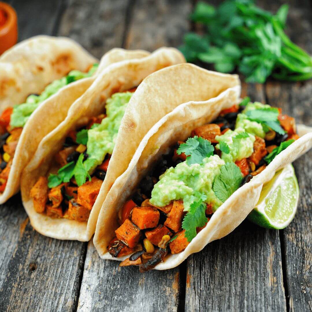 Plant-based tacos topped with guacamole.