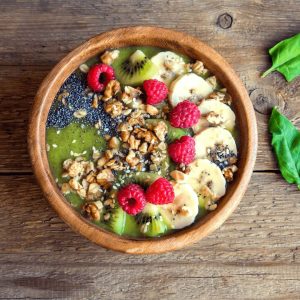 Green smoothie bowl, topped with fresh fruit seeds, and granola. 