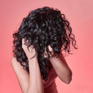 Young woman scrunching her curly hair. 