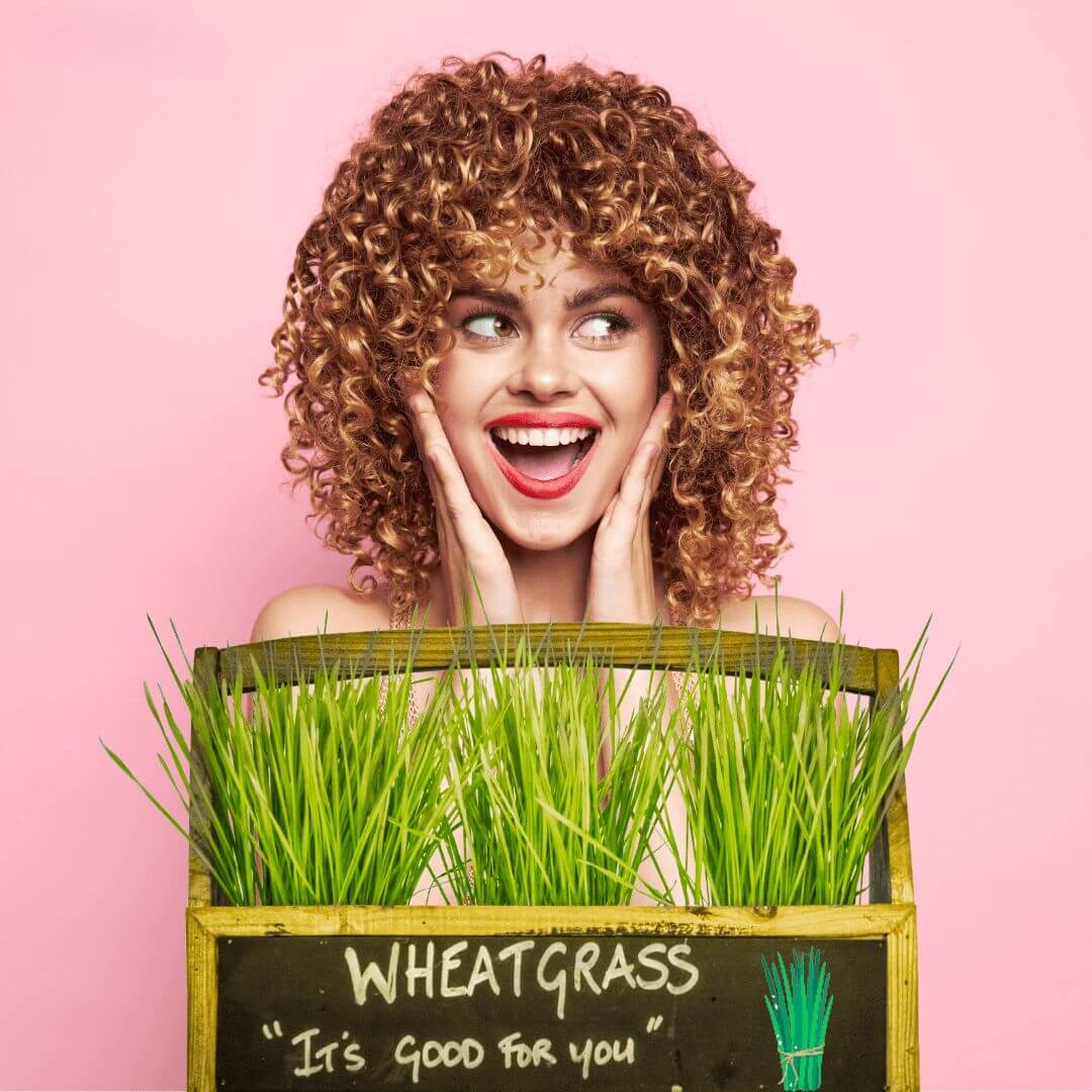 Young woman with curly hair in front of wheat grass.