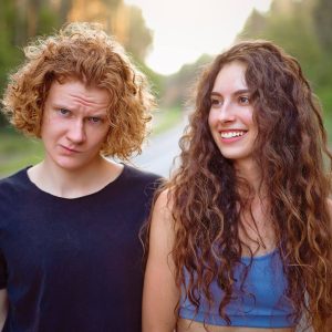 Guy and Girl with curly hair walking down a road. 