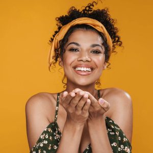 Girl with curly hair wearing a headband, holding her hands out. 