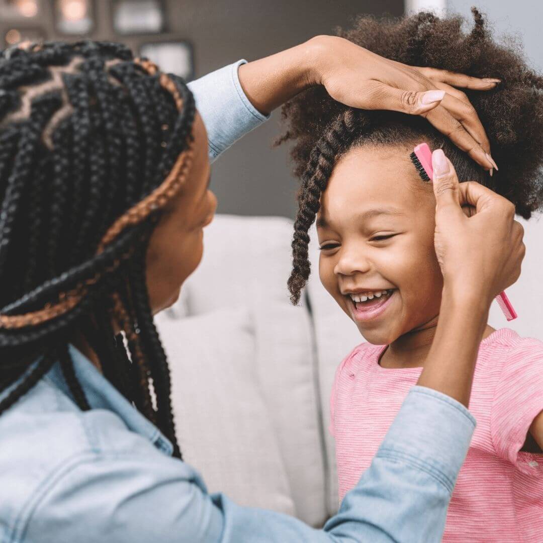 Mom combing daughter’s hair.