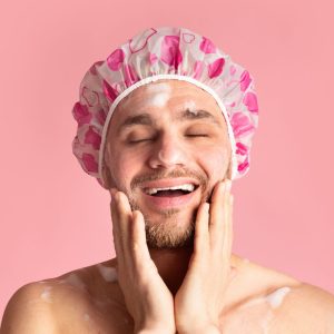 Guy wearing a shower cap, happy in the shower. 